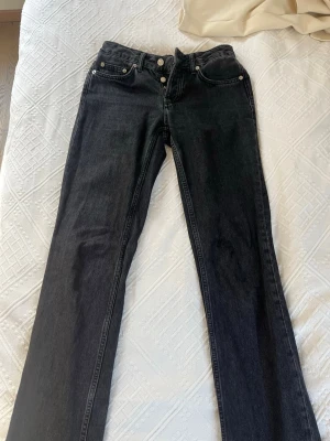 Svarta bootcut jeans med låg midja - Snygga svarta jeans med bootcut passform och låg midja. Klassisk femficksdesign och raka ben som slutar i en lätt utsvängning. 