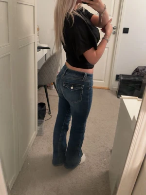 Blå bootcut jeans med låg midja - Snygga blå bootcut jeans från Gina Tricot i storlek 158 med låg midja och fickor med knapp bak. Jeansen har en lätt utsvängd passform. Säljer pga att jag har ett till par likadana.