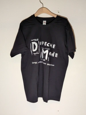 Svart Depeche Mode t-shirt storlek Large - svart t-shirt med Depeche Mode-tryck på framsidan. Klassisk passform med rund hals och korta ärmar. Perfekt för dig som gillar bandmerch och vill ha en stilren look. Storlek Large unisex
