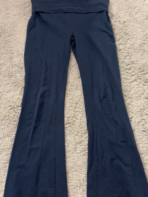 Mörkblå utsvängda leggings - Mörkblå leggings med utsvängda ben och hög midja. Mjukt och stretchigt material som sitter bekvämt. Perfekta för en avslappnad och trendig look. Inga synliga detaljer eller loggor.