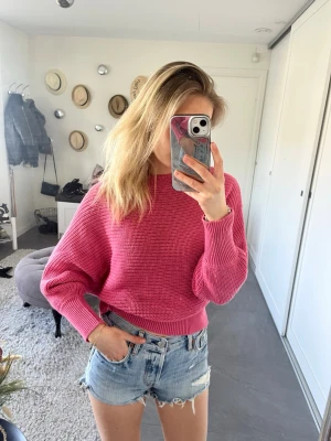 Rosa stickad cropped tröja - Säljer en snygg rosa stickad tröja med croppad passform och rund hals. Tröjan har långa ärmar med breda muddar och är stickad i ett mjukt material. Perfekt att styla med jeans eller kjol för en trendig look.