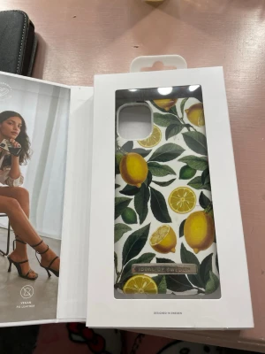 Mobilskal med citronmönster från iDeal of Sweden - Snyggt mobilskal från iDeal of Sweden med färgglatt citronmönster på vit bakgrund. Iphone 11/XR Skalet har detaljer i grönt och gult och är tillverkat i veganskt läder. Perfekt för dig som vill ha ett unikt och fräscht skal till mobilen.