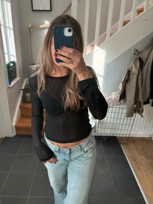 Svart mesh långärmad topp - Trendig svart mesh topp med lång ärm och tight passform. Tunt, genomskinligt material som ger en edgy look. 