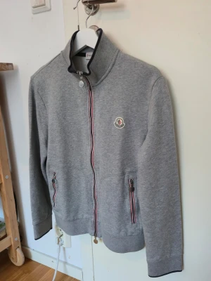 Grå zip-hoodie från Moncler - Snygg grå hoodie från Moncler med dragkedja och klassiska Moncler-loggan på. Mycket gott skick säger 9/10. Storlek M men passar S bättre. Sitter bra på mig som är 176cm. Garanterar att den är äkta. 