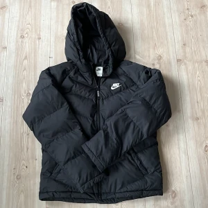 Svart pufferjacka från Nike - Säljer en svart vinter pufferjacka från Nike med huva och dragkedja framtill. Använd men i super fint skick!