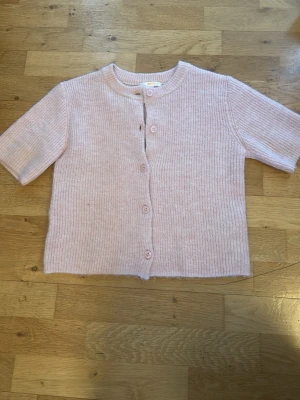 Ljusrosa stickad kofta med knappar - Söt ljusrosa stickad kofta med korta ärmar och rund hals. Den är inte använd mycket alls och är inte nopprig. storleken är 146/152 men är ganska stor i storleken också🥰