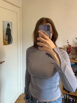 Ljusblå ribbad långärmad topp - Ljusblå  långärmad topp med ribbad struktur och figurnära passform. Ärmarna är lite utsvängda och splittade