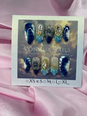BlueSiren (S);Medium Almond - Unika handgjorda press-on naglar i blått och vitt med special design och 3D-dekorationer i guld, pärlor och kristaller. Mix av design och medium lång mandelform, vissa naglar har nude bas och detaljer i ljusblått. Perfekt för dig som vill sticka ut med exklusiv design.S: 15 mm, 11,5 mm, 12 mm, 11 mm, 9 mm 