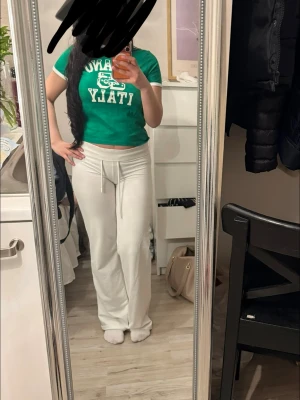 Grön croppad t-shirt med tryck - Grön croppad t-shirt med vit text och grafiskt tryck framtill. T-shirten har rund halsringning och korta ärmar. Perfekt för en avslappnad och trendig look.