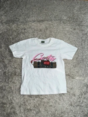 Vit cortiez t-shirt med tryck och text - Vit corteiz t-shirt med färgglatt tryck av en bomb med digital klocka och rosa text på framsidan. På baksidan står det 'NO TIME 4 LUV' i stora svarta bokstäver. Klassisk passform och rund hals, perfekt för dig som gillar statement-plagg. För fler frågor/bilder skriv privat.