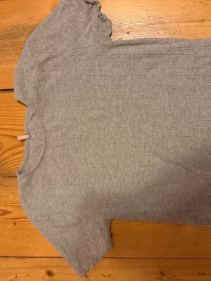 Grå ribbad t-shirt från ONLY - Säljer en enkel och stilren grå t-shirt från ONLY. T-shirten har korta ärmar, rund halsringning och är ribbad i materialet vilket ger en snygg struktur. Perfekt basplagg till garderoben.