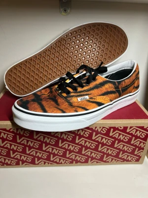 Vans sneakers (pris kan diskuteras) - Unika Vans sneakers med tigerinspirerat mönster i orange, svart och vitt. Klassisk låg modell med svart snörning, vit sula och den ikoniska Vans-loggan på sidan. Ovandelen är i canvas och yttersulan har det klassiska gummimönstret.