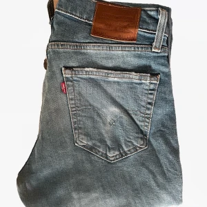 Levi's 511 ljusblå jeans - Säljer ett par ljusblå Levi's 511 jeans, straight passform. På bakfickan har en snusdose fade börjat ta form även! Dem är i fint skick med inga defekter utom slitningar men det är bara snyggt i mina ögon. 
