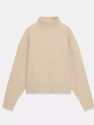 Beige stickad polotröja - Säljer en beige stickad polotröja med avslappnad passform och ribbade muddar vid hals, ärmslut och nederkant. Tröjan har en hög krage och är perfekt för lager på lager under kyliga dagar. Materialet ser mjukt och mysigt ut.