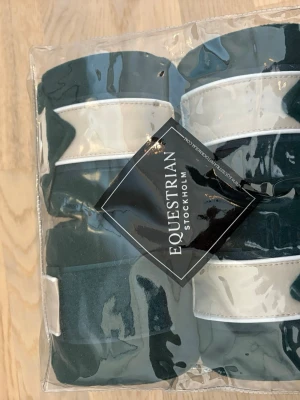 Mörkgröna benlindor Equestrian Stockholm - Säljer ett set med fyra mörkgröna benlindor från Equestrian Stockholm. Lindorna har en vit detalj och kommer i en praktisk genomskinlig förvaringsväska. Perfekta för hästintresserade som vill ha stilrena accessoarer till stallet. Helt oanvända så gott som nya. Priset kan diskuteras