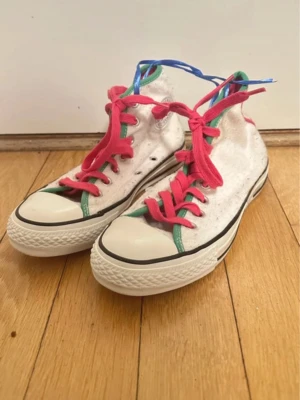 Vita Converse med rosa snören och gröna detaljer  - Unika vita Converse Chuck Taylor All Star med rosa snören, gröna detaljer och rosa sula. Klassisk hög modell med tåhätta i gummi och svart rand runt sulan. Köpt på loppis! Aldrig använd själv. (Sälj även på vinted)