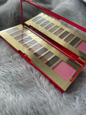 Ögonskuggspalett i rött och guld estee Lauder - Snygg ögonskuggspalett från estee Lauder med röd, guld och vit förpackning. Innehåller flera nyanser i neutrala toner samt en rosa skugga. Paletten har spegel och elegant design i hårdplast.