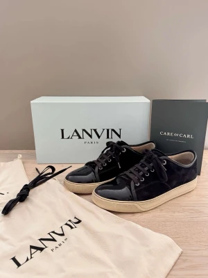 Lanvin- skor - Lanvin DBB1 Patent Cap Toe Sneaker Black | UK8 - EU42. Pris: 2,900kr. Gott skick med mindre defekter. Kvitto finns | köpt nya på CareofCarl. Kommer med box |Påse för bägge skor | Nya oanvända skosnören, originella.