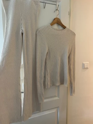 Beige ribbat loungewear-set - Två delat set från H&M . Stretchigt material. Byxan är i xs och tröjan i s men passar även xs. Tröjan har slits vid armarna. Aldrig använd då byxorna är för långa på mig. Köpt för 600kr men säljes för 280 kr 