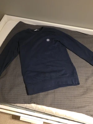 Mörkblå sweatshirt från Stone Island - Snygg mörkblå sweatshirt från Stone Island med rund hals och diskret logotyp på bröstet. Tröjan har en klassisk passform och är tillverkad i mjukt material, perfekt för en avslappnad stil.