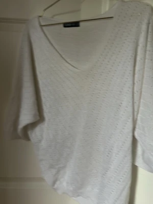 Vit glittrig topp från Cloud 5ive - Säljer en vit glittrig topp från Cloud 5ive i storlek S. Toppen har v-ringning och korta ärmar, samt ett lätt transparent material med diskret glittrig effekt. Perfekt för dig som vill ha en enkel men ändå extra touch på outfiten.