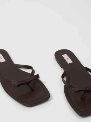 Bruna sandaler NELLY - Snygga bruna sandaler med tunna remmar och fyrkantig tå. Modellen har en minimalistisk design med en liten knut framtill och platt sula. Perfekta för en avslappnad och trendig look under varma dagar. Supergullig rosett uppe på