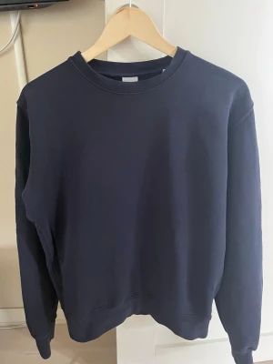 Mörkblå sweatshirt från Aspesi - En stilren mörkblå sweatshirt från Aspesi med rund halsringning och ribbade muddar vid ärmslut och nederkant. Tröjan har en klassisk passform och är tillverkad i mjukt material som passar perfekt till en avslappnad look.