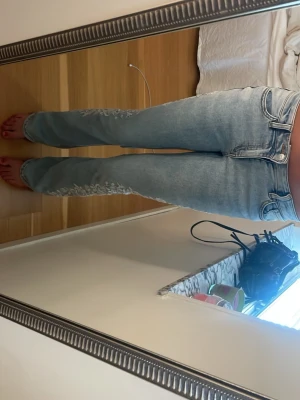 Ljusblå jeans med blommig brodyr - Säljer ett par ljusblå raka jeans med snygg vit blommig brodyr längs utsidan av benen. Jeansen har klassisk femficksmodell och normal midja. Perfekta för dig som vill ha något unikt och trendigt i garderoben!