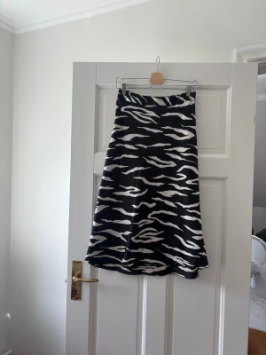 Jättefin svart/vit zebramöntrad midikjol ifrån Vero Moda  - Jättefin svart & vit zebramönstrad midikjol ifrån märket Vero Moda i storlek xs som är i bra skick och perfekt till sommaren🌸 Den är sval, skön och är i bra material. Kjolen har en väldigt fin passform, är enkel att styla, är unik och ser elegant ut. Den har tyvärr små små trådar som sticker ut(se bild) men som knappt syns någonting. Skriv om funderingar, lämna gärna omdöme och priset kan diskuteras lite😊