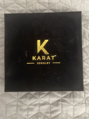 Guldkedja 21k Guld platerad Från Karat  - Säljer ett snyggt guldfärgat kedjeset från Karat Jewelry. Setet består av ett halsband och ett armband med tvinnad design, levereras i original ask. Perfekt för dig som vill ha en stilren och trendig accessoar med exklusiv känsla.