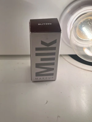 Milk Makeup Blitzed läppstift - Inte öppnad förpackning helt nySäljer ett läppstift från Milk Makeup i nyansen Blitzed. Färgen är mörk, nästan vinröd, och hylsan är vit med tydlig logga i silver. Stiftet har en rundad form och förpackningen är stilren och modern i plast.