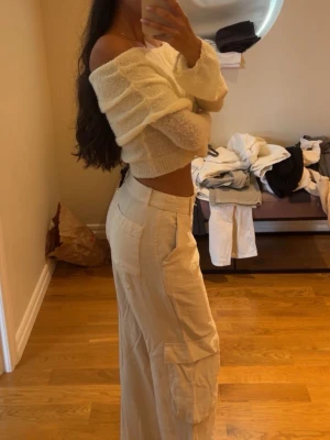 Beige cargobyxor med raka ben - Säljer ett par beige cargobyxor med raka ben och flera fickor på sidorna. Byxorna har hög midja och en avslappnad passform som ger en cool och trendig look. Perfekta för dig som gillar streetstyle och vill ha något bekvämt men ändå snyggt. Och tröjan 