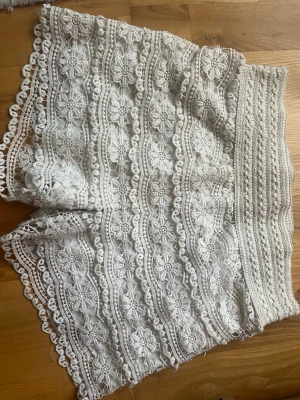 Vita virkade spets-shorts - Säljer ett par skitsnygga vita virkade shorts med  detaljerad blommig spets. Shortsen är stretchiga och kan därför passa S och M🥰 