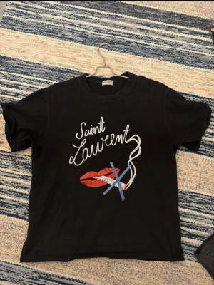 Svart Saint Laurent t-shirt med tryck - En saint lauren FW2017 ”no smoking” tshirt. Köpt på Plick där det medföljde ett kvitto från tidigare ägaren som jag självklart skickar med Har blivit lite mindre i tvättmaskinen så sitter som en S Lite cracking på trycket