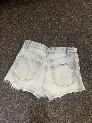 Ljusblå jeansshorts med slitna detaljer  - Säljer ett par ljusblå jeansshorts från Zara. Hyfsat använda men fortfarande i bra skick! De är highwaisted. Säljer då de är för små.