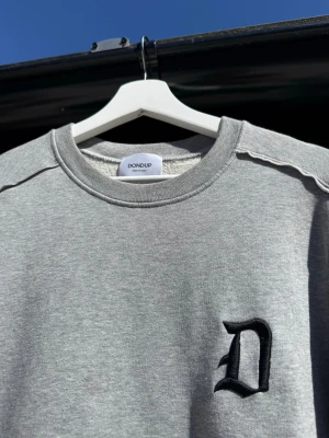 Grå sweatshirt från Dondup - Snygg grå sweatshirt från Dondup med svart broderad D på bröstet. Perfekt för en avslappnad och stilren look. Fräsch och sällan använd! Inga defekter eller märken. Skriv vid frågor!