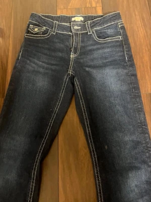Mörkblå jeans från Gina Tricot - Snygga mörkblå jeans från Gina Tricot med kontrasterande vita sömmar och klassisk femficksmodell. Jeansen har en rak passform och är tillverkade i denim. Perfekta för en trendig och avslappnad look.