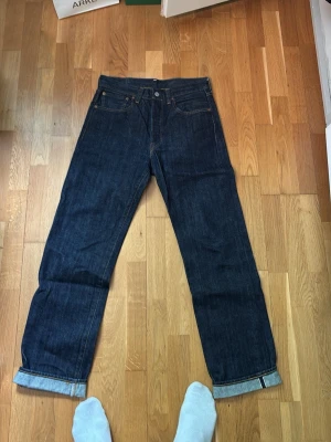 Mörkblå raka jeans från Levi's - Säljer ett par klassiska mörkblå jeans från Levi's med rak passform och uppvikta benslut. Jeansen har fem fickor, knappgylf och är tillverkade i kraftig denim. Perfekta för en clean och tidlös look. (Köpte från en grabb som gjorde dom egendesignade)