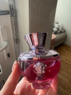 Versace Bright Crystal Eau de Parfum 100ml - Lyxig parfym från Versace i en rund, genomskinlig flaska med rosa doftvätska och silverfärgat lock. Flaskan har Versaces ikoniska Medusa-huvud i silver på framsidan och rymmer 100 ml Eau de Parfum. Perfekt för dig som gillar eleganta och feminina dofter. Sprayad en gång