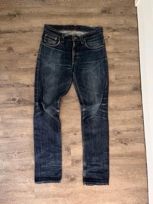Nudie Jeans Herr Grim Tim Med Tvätt - Säljer ett par riktigt schyssta Nudie Jeans i modellen Grim Tim med en väldigt skön tvätt!  Jeansen är i gott skick, har lite slitningar som ni ser på bild men inget i skrevet eller så☀️ Storlek är 30/32 och sitter i en slim fit passform!   🚚Fraktas alltid inom 24h📦