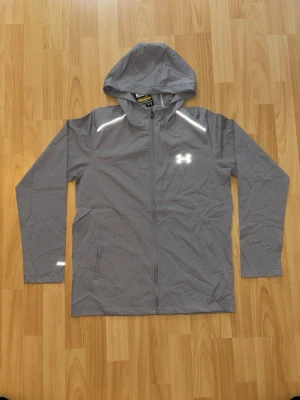 Under Armour Jacka - Grå Under Armour jacka/vindjacka helt ny i storlek L, men passar som M/S. Kommer med dustbag och tags. Mått finns. Kom gärna på med prisförslag och frågor! 🙏💬 
