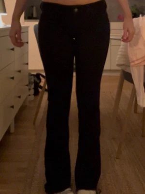 Svarta bootcut jeans - Säljer ett par svarta bootcut jeans med hög midja och klassisk femficksdesign. Jeansen har en snygg passform som sitter tajt över höfterna och låren och släpper ut nedtill. Perfekta till sneakers eller boots.