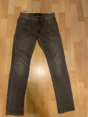 Grå slim fit jeans från Replay - Snygga grå jeans från Replay i slim fit-modell. Klassisk femficksdesign med dragkedja och knapp framtill. Jeansen har en tvättad look och är tillverkade i ett mjukt denimtyg som ger en skön passform. PS Lappen där bak sitter lite löst. Modellen är wallys och storleken är 12A vilket motsvarar 152 cm. Passar dig runt 150-165 cm. Pris kan diskuteras vid snabb affär! För mer frågor skriv i DM. 