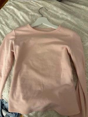 Ljusrosa långärmad topp - En enkel och stilren ljusrosa långärmad topp med rund halsringning. Perfekt basplagg att matcha med olika outfits. Mjuk och bekväm, tillverkad i bomullsmaterial.