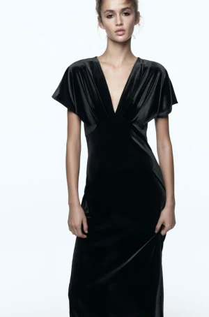 Svart sammetsklänning med v-ringning - Elegant svart långklänning i mjuk sammet med djup v-ringning och korta, vida ärmar. Klänningen har en figurnära passform och faller snyggt längs kroppen. Perfekt till tillställningar🖤Endast använd vid några få tillfällen, så i nyskick. Skriv för flera bilder. 