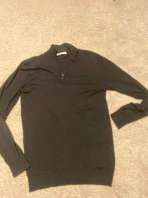 Svart merinoullströja med half zip - Snygg svart stickad tröja från Cubus i 100% merinoull. Tröjan har en stilren half zip-dragkedja vid halsen och lång ärm. Perfekt för dig som gillar en enkel men klassisk look.