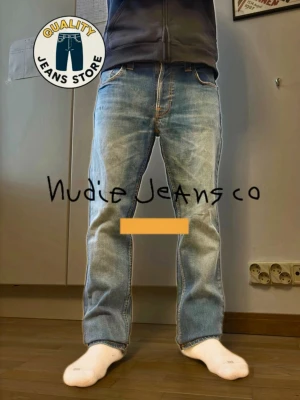 Blå raka jeans från Nudie Jeans - Säljer ett par klassiska blå jeans från Nudie Jeans med raka ben och snygga kontrastsömmar. Jeansen har fem fickor, läderpatch bak i midjan och den ikoniska broderade vågen på bakfickan. Tillverkade i slitstark denim, perfekta för en avslappnad stil.