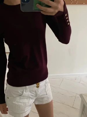 finstickad vinröd tröja med guld knappar  - finstickad vinröd tröja med guldknappar längst ut på ärmen.