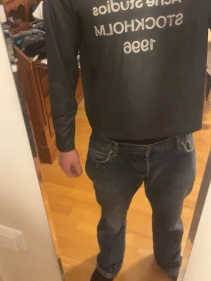 Grå långärmad tröja Acne Studios - Snygg grå långärmad tröja från Acne Studios med tryck 'STOCKHOLM 1996' på bröstet. Tröjan har en avslappnad passform och är tillverkad i mjukt material, perfekt för en casual och trendig look.