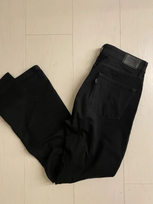 Svarta Levi's jeans herrmodell - Snygga svarta jeans från Levi's med klassisk femficksdesign och raka ben. Jeansen har en svart läderpatch bak i midjan och diskret Levi's-logga på bakfickan. Perfekta till en streetwear-look eller för en clean stil.